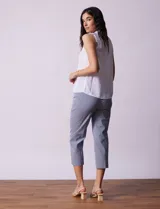 Blusa blanca de gasa marca Zac & Rachel, sin mangas, con cuello a la base con frunce, escote en V con botones, delantera plisada y apliques en crochet.