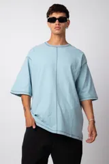 Remera negra oversize con mangas cortas y costuras a la vista en color blanco.