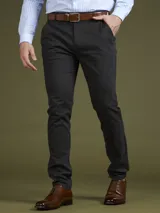 Pantalón de vestir azul marino, de corte slim fit, con bolsillos laterales y traseros. Se ajusta a la cintura con cinturón de cuero marrón.