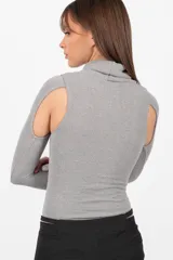 Body gris de tejido de punto con cuello alto y mangas largas. Presenta aberturas en los hombros y broches en la entrepierna.