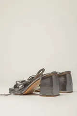 Sandalias plateadas de cuero con tacón bloque y tiras finas para atar al tobillo.