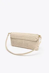 Bolso alargado color beige con diseño trenzado, asa bandolera y tirador con pulsera de mano. Incluye bolsillo interior y cierre con solapa y botón imantado.