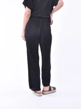 Pantalón negro de tiro alto con cintura elástica y textura plisada. Corte recto y holgado.