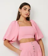 Blusa cropped color rosa con escote cuadrado y mangas cortas abullonadas.