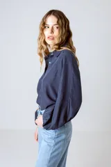 Camisa blanca de lino y lyocell, de corte clásico, con cuello camisero y mangas largas abullonadas con puños abotonados.