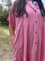 Vestido corto rosa de fibrana, corte oversize, con cuello camisero, mangas cortas y bolsillos laterales.