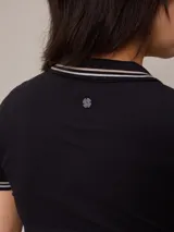 Remera polo blanca de piqué con cuello sin botones y mangas cortas con ribete a rayas rojas y azules. Corte clásico.