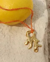 Collar con dije de bronce macizo con forma orgánica o de coral, suspendido de un hilo de seda natural color naranja.