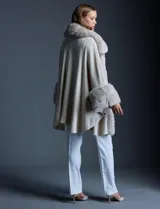 Ruana tejida color crema de la marca Adrienne Vittadini, con cuello, delantera y puños con aplique en símil piel. Delantera con abertura central y botón trenca.