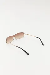 Lentes de sol con lentes marrones degradé sin marco y patillas doradas.