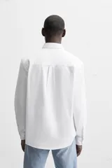 Camisa azul marino de corte regular fit, confeccionada en tejido de algodón Oxford. Tiene cuello abotonado, manga larga con puños abotonados, bolsillo de parche en el pecho y cierre frontal con botones.