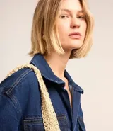 Vestido corto de jean azul con cuello camisero, escote en V, mangas cortas, dos bolsillos delanteros y corte recto.