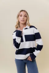 Sweater de manga larga con diseño de rayas anchas horizontales en azul marino y blanco. Posee cuello polo con cartera de botones y calce relajado.