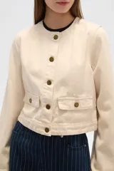 Chaqueta corta de algodón con estampado animal print en tonos grisáceos, cuello redondo, cierre frontal con botones a presión, bolsillos de parche en el pecho y corte recto.