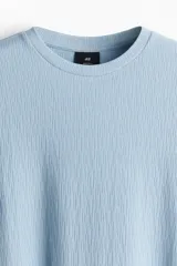 Remera celeste de punto texturizado, corte recto y cuello redondo.