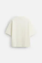 Camiseta rosa de corte recto, cuello redondo y manga corta. Estampado con efecto grabado combinado a tono en la espalda.