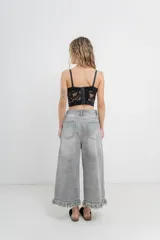 Pantalón jean gris de tiro alto, corte ancho y largo 3/4 con detalle de flecos en el ruedo.