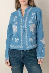 Camisa de jean celeste con bordados de flores blancas en hilo de seda, cuello mao y cierre frontal con botones.