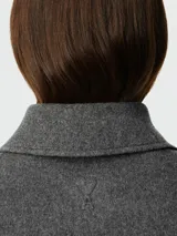 Chaqueta corta gris de lana con corte cuadrado, cuello clásico, cierre abotonado y bolsillos de parche.