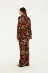 Pantalón acampanado con estampado floral multicolor sobre fondo negro. Corte ajustado con bajo ancho.