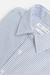 Camisa de hombre regular fit confeccionada en tejido de algodón a rayas verticales azules y blancas. Tiene cuello italiano, manga larga con puños abotonados y cierre frontal con botones.