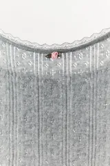 Top gris de algodón con tirantes finos y escote redondo con detalle de puntilla. Presenta una pequeña flor combinada en el pecho.