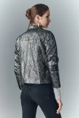 Camisa de cuero ovino con estampado de piel de serpiente multicolor y detalles metalizados. Presenta un cuello alto, botones a presión con logo de alas y puños de tejido de punto gris.