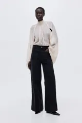 Jean de denim de algodón negro con leve stretch, pierna ancha, corte ajustado de cintura a cadera y holgado de muslo a bajo. Tiene cintura de tiro alto con cierre y botón, y bolsillos de parche delanteros y traseros.