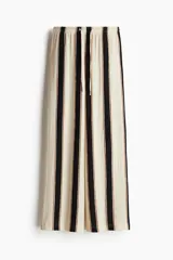 Pantalón de punto color crema con rayas verticales negras y marrones, de corte holgado y tiro alto, con cintura elástica y cordón ajustable.