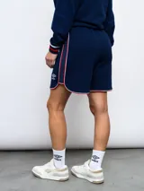 Short deportivo azul marino con ribetes blancos y rojos, y escudo del Club Nacional de Football bordado en la pierna derecha.