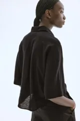 Camisa negra de lino y viscosa, corte holgado, mangas al codo, cuello clásico y cierre con botones.