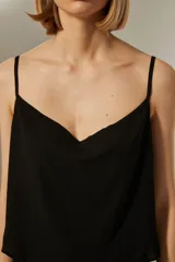 Musculosa blanca de poliéster con breteles finos, cuello drapeado y corte holgado.