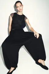 Top de manga caída, con efecto de doble capa. La capa exterior es negra y ajustada, mientras que la capa interior, visible en mangas y cuello, es de color marrón topo.