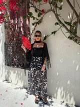 Falda larga de tela estampada con motivos florales en tonos marrones, negros y violetas. Tiene elástico en la cintura y corte acampanado.