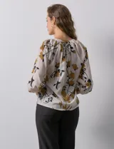 Blusa de gasa verde con estampado floral blanco y celeste, cuello a la base con escote en V y mangas 3/4 fruncidas.