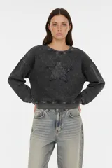Buzo gris oscuro con efecto acid wash, cuello redondo, manga larga y un estampado de estrella en el frente.