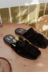 Sandalias tipo mule de cuero color marrón chocolate, con diseño de tiras anchas cruzadas y suela plana.