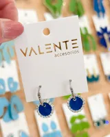 Par de aros colgantes plateados con dije circular azul rodeado de strass.