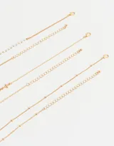 Set de tres collares dorados de diferentes largos. Uno con perlas sintéticas, otro con cruces de metal y el tercero con dije de corazón con alas.