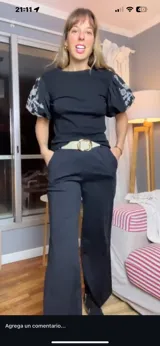 Blusa negra de mangas cortas abullonadas con bordado floral en blanco y cuello redondo.