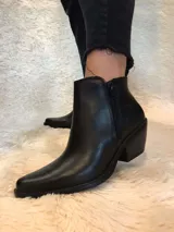 Botín de cuero color borgoña, con punta fina, cierre lateral y taco bajo de madera.