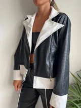 Campera de cuero sintético negro y blanco con diseño contemporáneo y cierre frontal.
