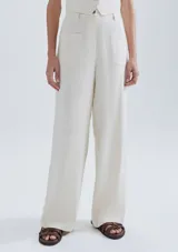 Pantalón de vestir color beige, de corte ancho y tiro alto, con bolsillos delanteros y traseros.