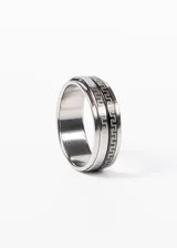 Anillo de acero quirúrgico color plateado con banda giratoria y diseño de guarda griega en negro.