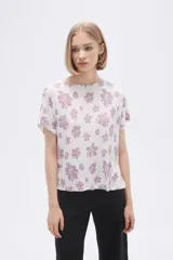 Remera blanca con estampado floral en color lila, de corte holgado y mangas cortas.
