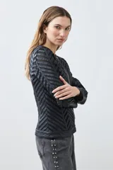 Chaqueta negra de cuero sintético con diseño acolchado en forma de espiga y detalles de tul.