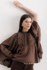 Camisa color marrón con cuello mao, mangas largas abullonadas y detalle de volados en el frente.