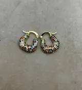 Aros tipo argolla gruesa con forma de herradura, bañados en tono dorado y completamente incrustados con piedras de strass de colores variados (rojo, azul, verde, naranja, blanco, etc.).