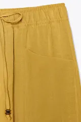 Pantalón color verde oliva de tiro alto, corte ancho y largo 7/8. Tiene cintura elástica ajustable con cordón, bolsillos de plastrón en delantero y espalda.