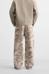 Pantalón de jean de corte recto con estampado abstracto en tonos beige, marrón y gris.